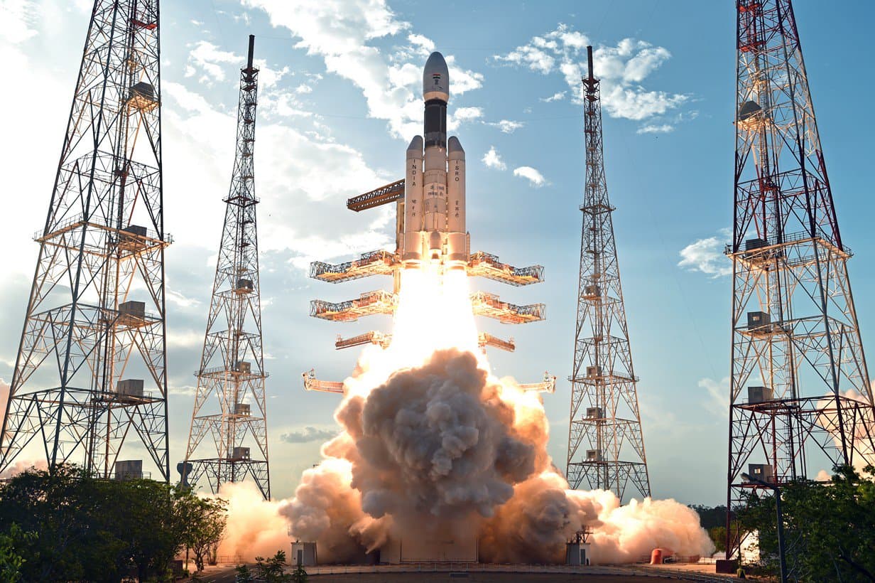 An LVM-3 rocket lifting off between four lightning towers at the Satish Dhawan Space Centre