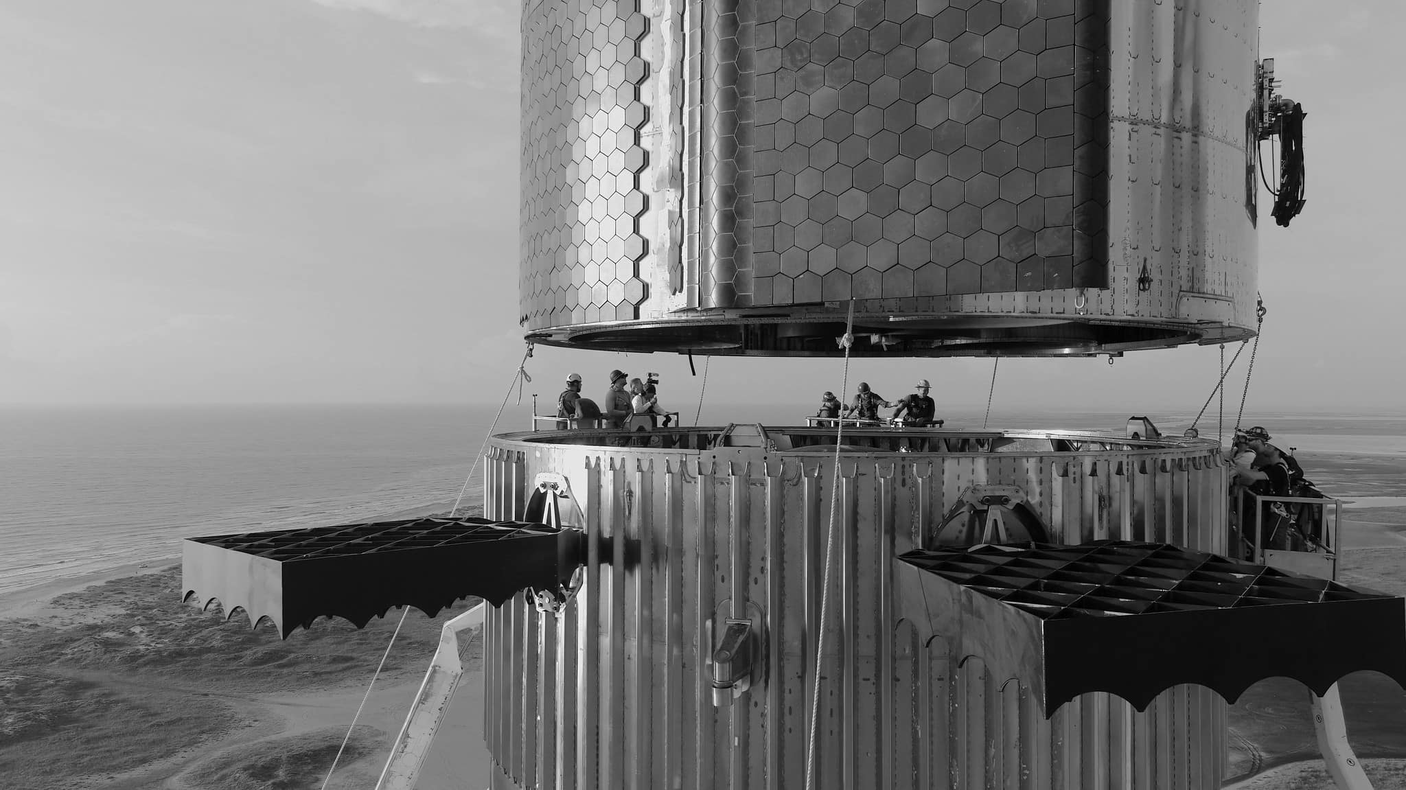Black and white photo of workers stacking a Starship upper stage on a booster
